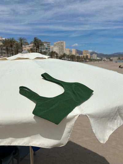 Top deportivo verde del bikini sostenible Mani Palm sobre sombrilla blanca en playa mediterránea - tejido reciclado ECONYL - CIRCU